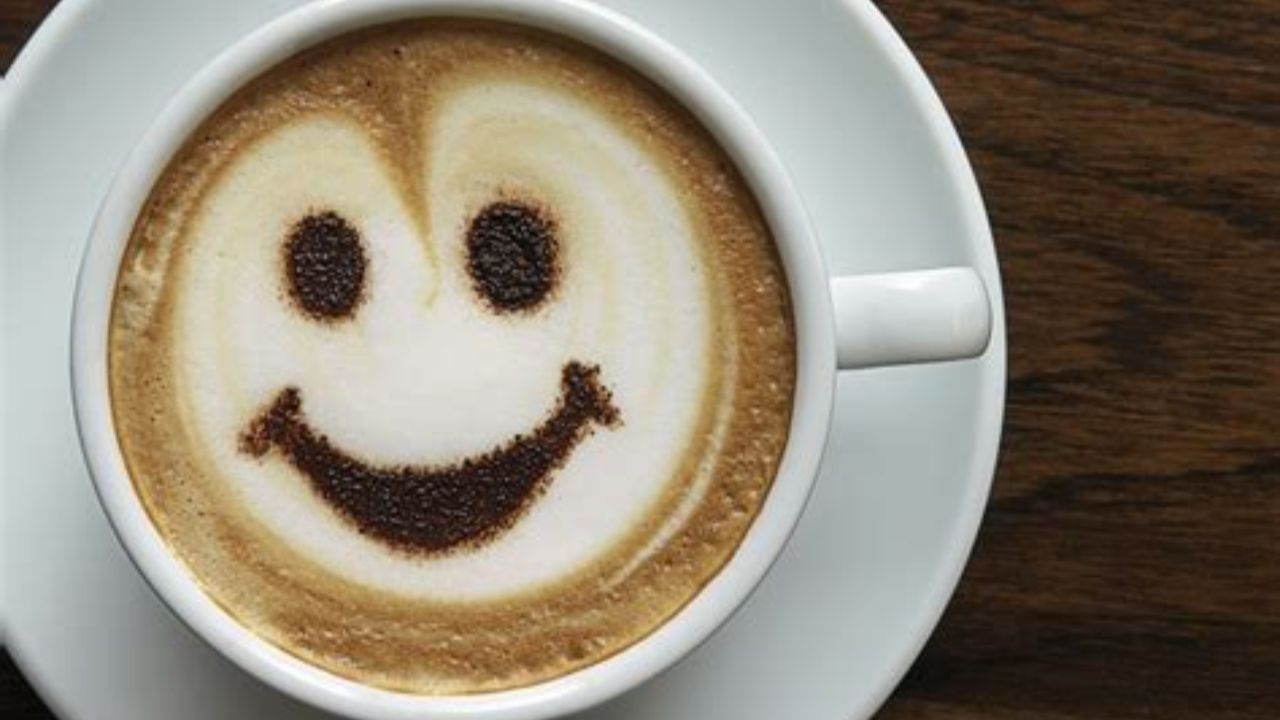 Cup of coffee in white mug on wood table. Foam in cup makes smiley face